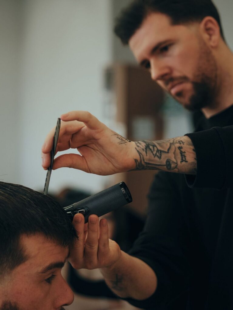 Barber met tatoeages knipt een klant, content voor een barbershop